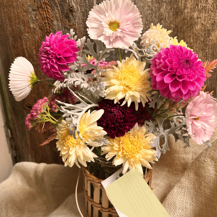 mums and dahlias in a footed vase with green background